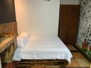 ein kleines Schlafzimmer mit einem Bett mit weißer Bettwäsche in der Unterkunft Gardens House, Airport Juan Santamaría, Alajuela, San José in Alajuela