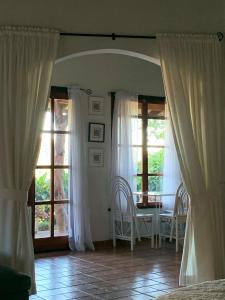 1 dormitorio con cortinas blancas, mesa y sillas en Bungalows Sanlaz, en Barrio Jesús