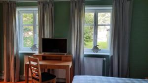a bedroom with a desk with a television and two windows at Ferienhaus am Elbdeich in Sankt Margarethen