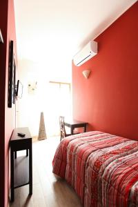 ローマにあるL'Oasi Verde a San Pietro apartmentの赤い壁のベッドルーム(ベッド1台、テーブル付)