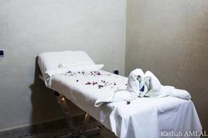 uma cama de hospital com toalhas brancas e flores em kasbah amlal em Tinghir