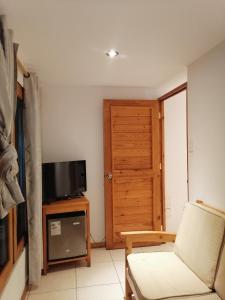 a living room with a chair and a television at Hospedaje PILARES DE BOCAPAN in Bocapán