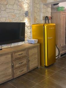 Cette chambre dispose d'un réfrigérateur jaune et d'une télévision. dans l'établissement FRENKI APARTMENT BY THE SEA, à Siviri