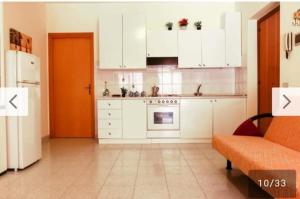 a kitchen with white cabinets and an orange couch at Casa Vacanze Amici dell' Etna in Giardini Naxos