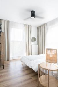 a white bedroom with a bed and a table at Tuyo Apartments Bokserska in Warsaw