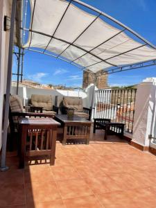un patio con mesas y sillas bajo un dosel en Casa Grande Hornos 18 en Cáceres