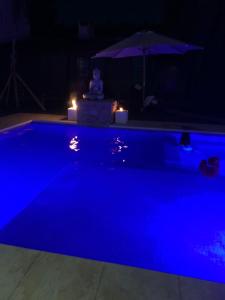 a blue swimming pool at night with an umbrella at Like at Home Ezeiza in Ezeiza