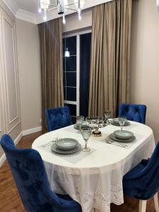 uma mesa de jantar com cadeiras azuis e uma toalha de mesa branca em Apartments in the Babylon residential complex em Almaty