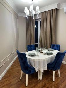 a dining room with a white table and blue chairs at Apartments in the Babylon residential complex in Almaty
