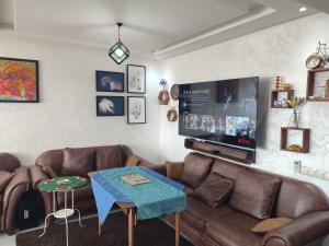 a living room with leather couches and a flat screen tv at L'Orchidée de Kénitra in Kenitra