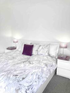 a white bed with a purple pillow on it at Caithness Holiday Home in Pontypool