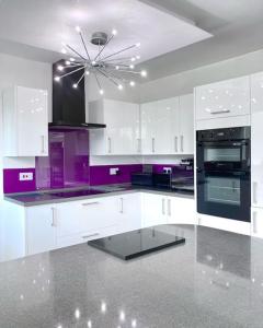 a kitchen with white cabinets and purple appliances at Caithness Holiday Home in Pontypool