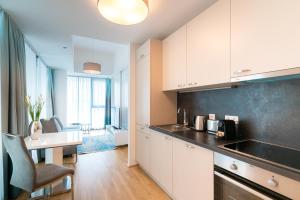 a kitchen with white cabinets and a table in a room at Vienna Residence, Marina Tower - Danube in Vienna