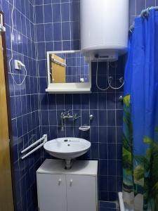 a blue tiled bathroom with a sink and a mirror at Apartman Lucy in Baošići