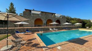 a swimming pool with chairs and an umbrella at Villa Gosparini in Lisciano Niccone