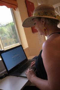 a woman in a hat sitting at a laptop computer at BELIZE TROPICAL DREAM VILLAS in San Pedro