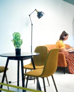 a woman sitting on a couch with a table and a lamp at Hotel Orfeas in Xanthi