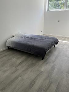 a bed in a white room with a wooden floor at Loft épuré avec parking privé. in Saint-Symphorien-dʼOzon