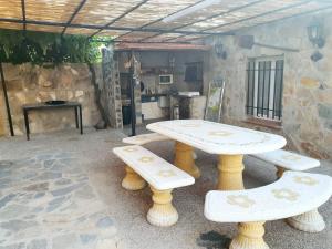 a picnic table and benches in front of a kitchen at El lazarillo de tormes in Escalona