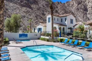 a swimming pool with chairs and a house at Legacy Villas private 3 bedroom 3 bath villa with view, steps to pool, bikes and arcade game included in La Quinta