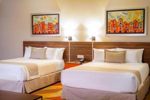two beds in a hotel room with paintings on the wall at Metria Hotel in León