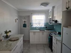 a kitchen with white cabinets and a window at Flamingo Park Langebaan, 2 Bedroom Apartment in Langebaan