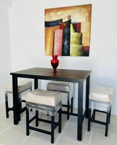 een tafel met stoelen en een vaas erop met een schilderij bij HNG APARTMENT, LINDO LUGAR, VENGA Y LO PASARÁ BIEN in Victoria
