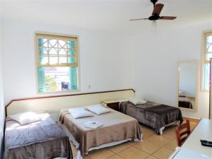 a room with two beds and a ceiling fan at Grande Hotel Bragança in Bragança Paulista