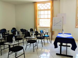a room with tables and chairs and a white board at Grande Hotel Bragança in Bragança Paulista