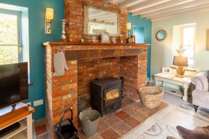 a living room with a brick fireplace with a mirror at Meadow Barn - Norfolk Cottage Agency in North Walsham