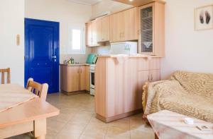 a kitchen with a blue door and a living room at STUDIOS ATHENA in Megalochori