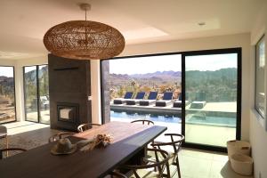 a dining room with a table and a view of a pool at Amaru Muru - Luxury Retreat with Pool/Hot Tub/Yoga in Joshua Tree