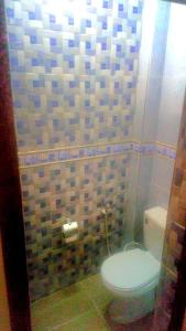 a bathroom with a toilet and a tiled wall at elkbira in Salé