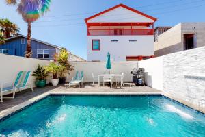 Una piscina con mesa y sillas y una casa. en Dolphin Paradise Unit B, en South Padre Island