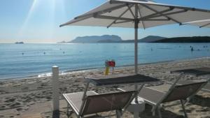 uma mesa e cadeiras numa praia com um guarda-sol em Hotel Luna Lughente em Olbia