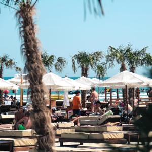 einen Strand mit Leuten, die auf Liegestühlen und Sonnenschirmen sitzen in der Unterkunft Mamaia Beach Condos 1 in Năvodari