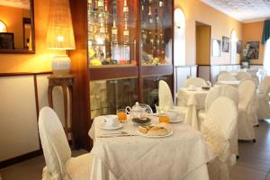 a dining room with white tables and white chairs at Hotel Nespolo D'Oro in Lariano