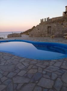 a blue pool on a stone patio with a castle in the background at Villas El Paradiso in Kouroúpi