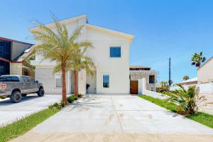 a white house with a palm tree in a driveway at Dolphin Paradise Unit A in South Padre Island