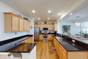 cocina grande con armarios de madera y encimeras negras en The Sandbridge Dunes - Island Sunrise 317, en Virginia Beach