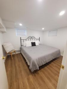a white bedroom with a bed and a chair at 1 Bedroom Lower Level Suite in Burlington -The Jacob at Bellwood in Burlington