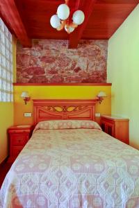 1 dormitorio con cama y pared de piedra en Apartamentos Rurales Las Cuendias, en Perlunes