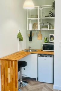 a kitchen with white cabinets and a wooden counter top at Le Tropical - Studio avec terrasse in Angoulême