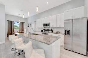 a kitchen with white cabinets and a counter with white stools at Seashell of the Ball in Cape Coral