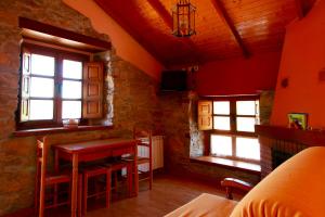Habitación con mesa, sillas y ventanas. en Apartamentos Rurales Las Cuendias, en Perlunes