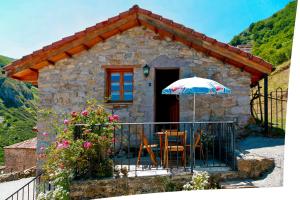 a small stone house with a table and an umbrella at Apartamentos Rurales Las Cuendias in Perlunes