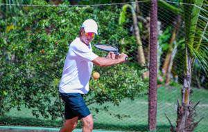 a man holding a tennis racket on a court at Bangalô Kauli Seadi Eco-Resort in São Miguel do Gostoso +26 photos
