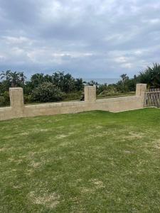 a stone wall in a field of grass at Wild coast Sea view House in Port Edward