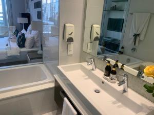 uma casa de banho com um lavatório, uma banheira e um espelho. em Sandton Skye Stylish Apartment free WIFI & Gym em Joanesburgo