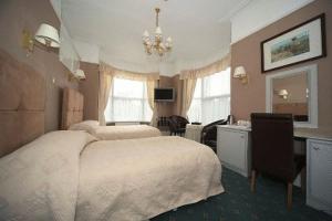 a bedroom with a large white bed and a desk at Eskdale Lodge in Sale